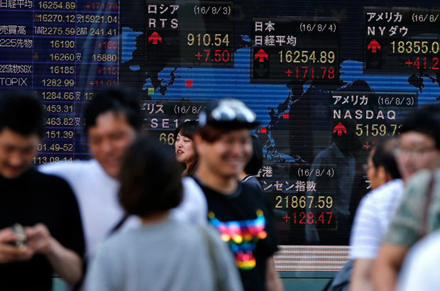 Coreia do Norte, Japão, Kim Jong-un, corrida armamentista, Juche - Pessoas passam diante de um painel eletrônico com índices da Bolsa de Valores Nikkei em Tóquio em16 de junho de 2016 (Shuji Kajiyama/AP)