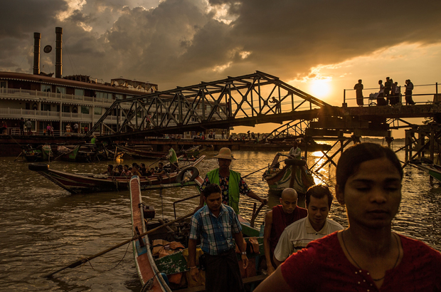 Myanmar, Birmânia, história, violência, rohingya, refugiados, muçulmanos - O sol brilha à distância enquanto pessoas viajam em barcos e passam o tempo no cais em embarcações ou nadando, antes das eleições de 8 de novembro, em Yangon, Birmânia, em 7 de novembro de 2015 (Lam Yik Fei/Getty Images)