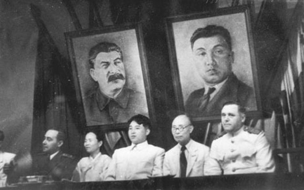 Kim Il-sung (centro), numa reunião do Partido Comunista dos Trabalhadores da Coreia do Norte, em Pyonyang, em 1946. Atrás dele está uma foto de Stalin (esq.), responsável pela morte de dezenas de milhões de russos e pessoas da União Soviética, e um retrato próprio (dir.) (Reprodução)