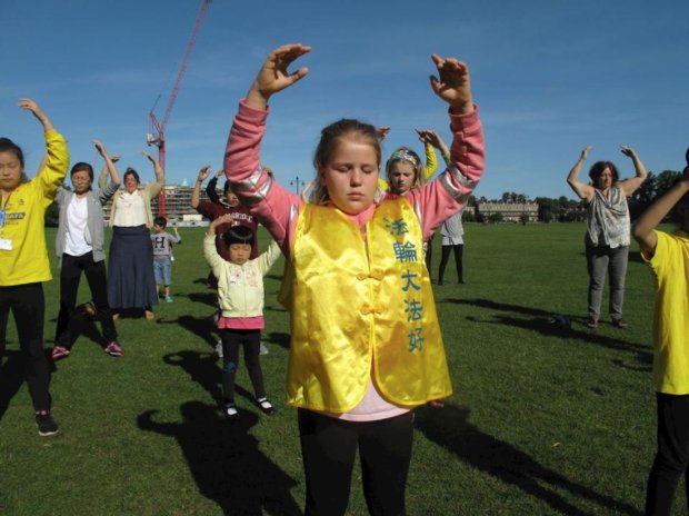 Ann Teurlings (ao fundo à direita) e sua filha Ili (centro) praticam os exercícios de pé do Falun Gong com o grupo local (Cortesia de Ann Teurlings)